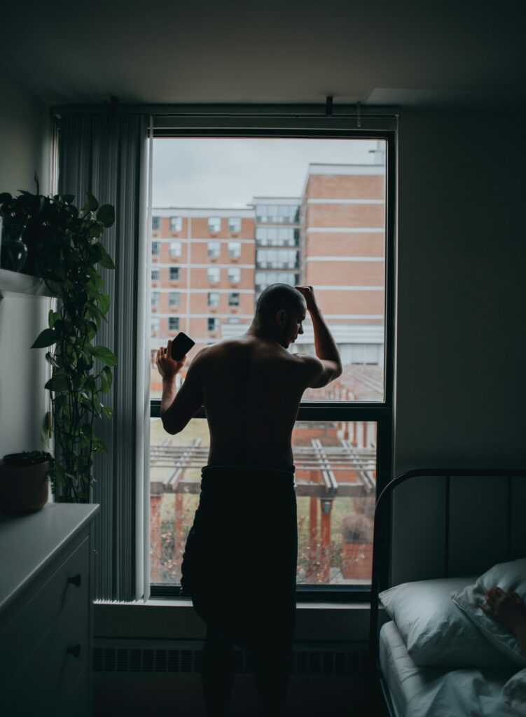 man standing by the window beside bed