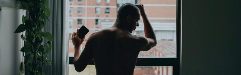 man standing by the window beside bed